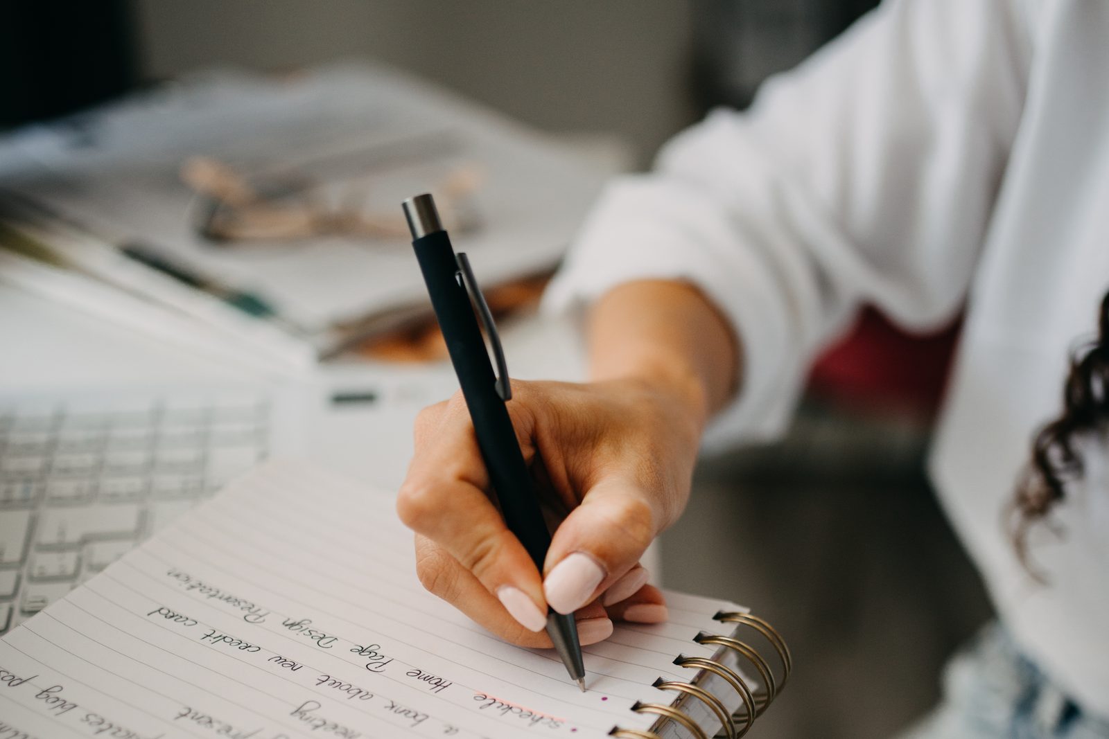 A woman writing in a spiral notebook, close up