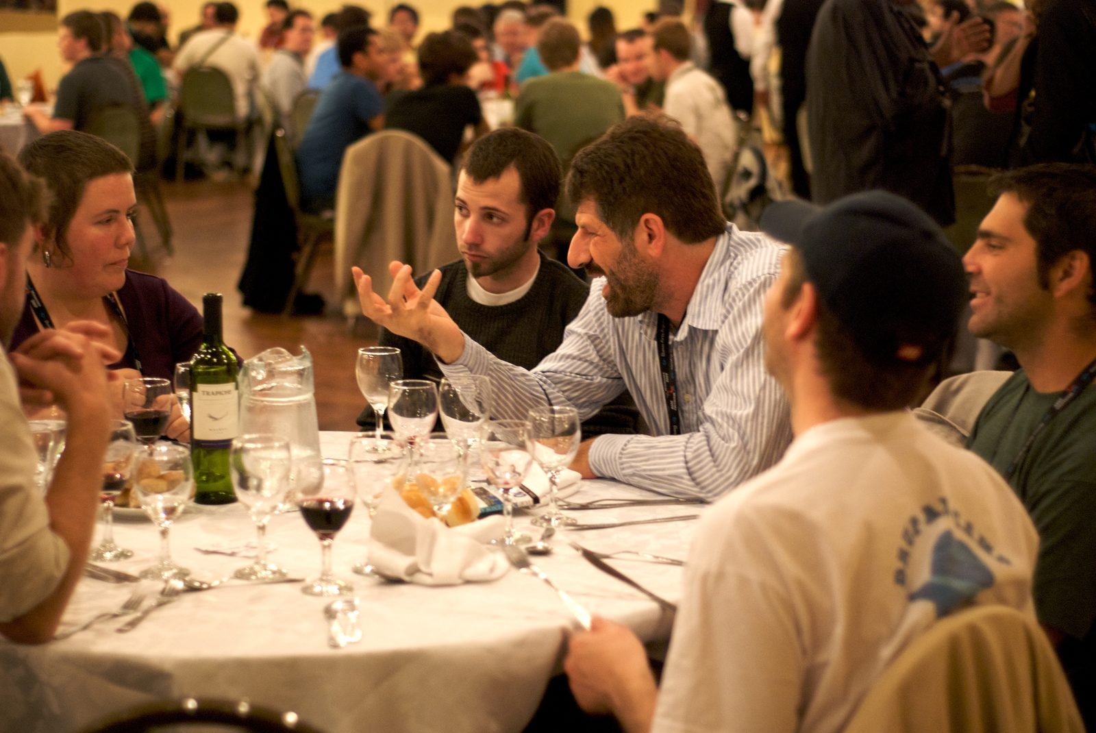 A man gesturing with his hands while talking at a dinner table