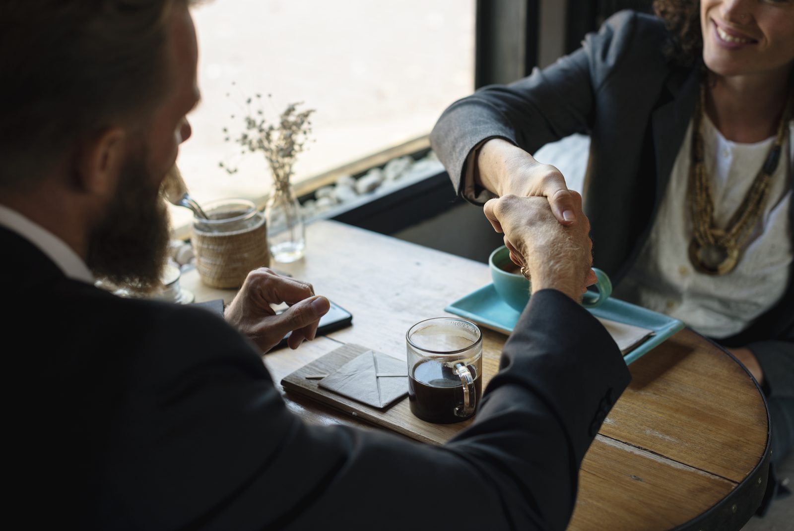 Two people shaking hands at a coffee shop